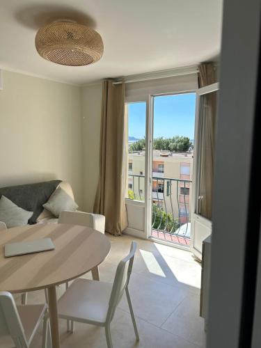 un salon avec une table et des chaises et une fenêtre dans l'établissement Le Cocon des Floréal, à Bandol