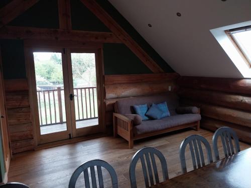 a living room with a couch and a table and chairs at Fir Lodge in Kings Lynn