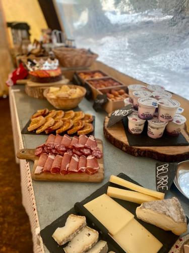 une table avec différents types de fromages et de viandes dans l'établissement Eco Bivouac village igloos Annecy - LE SEMNOZ - à 20 minutes d'Annecy, à Annecy