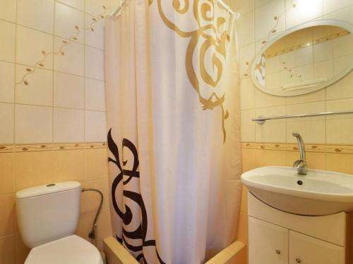 a bathroom with a toilet and a sink and a shower curtain at Pokoje Mariola in Karwia
