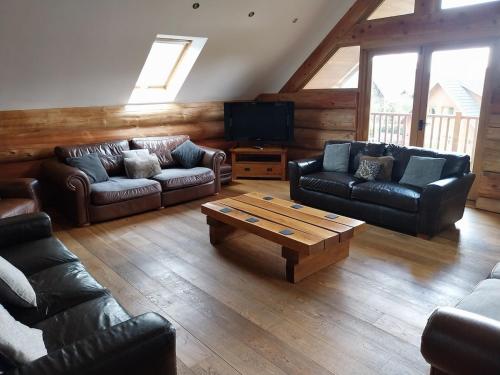 a living room with leather couches and a coffee table at Fir Lodge in Kings Lynn