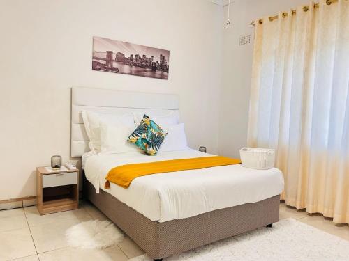 a bedroom with a bed with a yellow blanket at Josys Place in Bulawayo