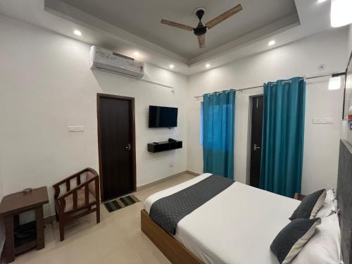 a bedroom with a bed and a tv and blue curtains at Ashoka Hotel in Begusarai