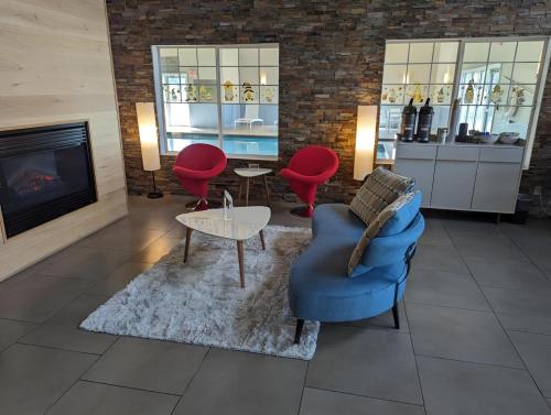 a living room with a blue chair and red chairs at Country Inn & Suites by Radisson, Chippewa Falls, WI in Chippewa Falls