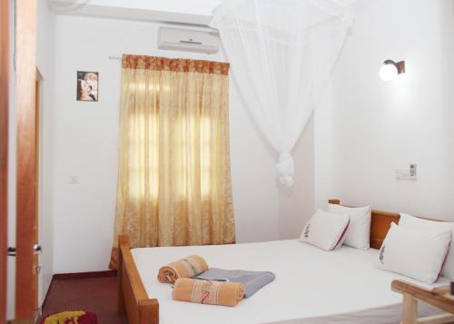 a bedroom with a white bed and a window at Pravindi Guest Home in Mirissa