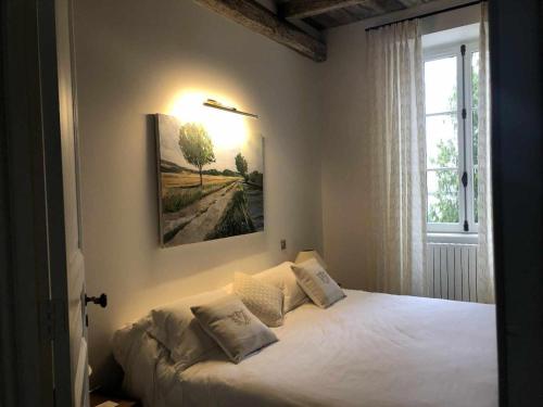 - une chambre dotée d'un lit blanc avec une photo sur le mur dans l'établissement Immeuble historique au pied du Château de Jonzac, à Jonzac