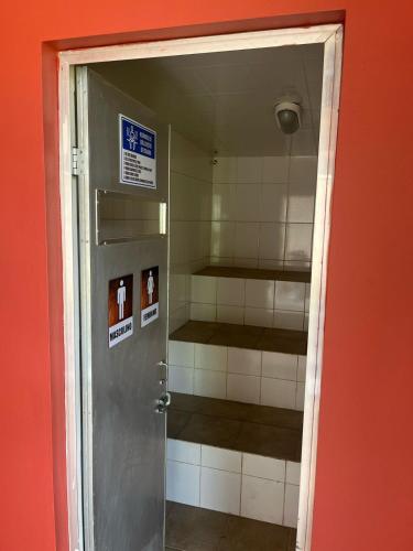 a door to a bathroom with a room with shelves at Pousada Apear in Andradas