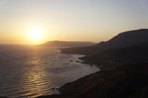 a sunset over the ocean with a mountain at Akrotirio Tainaro House in Marmari