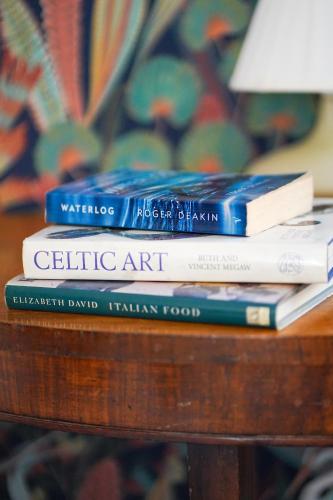 a stack of books sitting on top of a table at NEW The Old Smokehouse Central, Bohemian Room in Berwick-Upon-Tweed