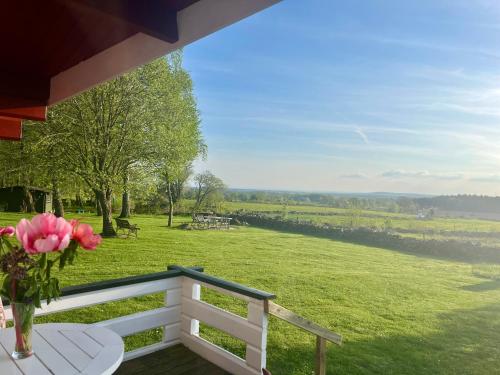 a vase of flowers on a porch with a view of a field at Naturnära Fritidsboende, Tomtebo - YinTorp in Arkelstorp