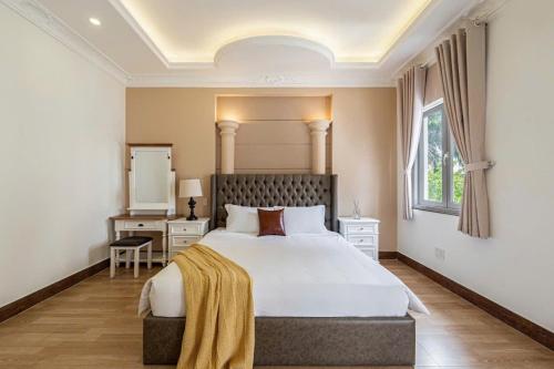 a bedroom with a large white bed and a window at Villa La Rose Blanc Thảo Điền in Ho Chi Minh City