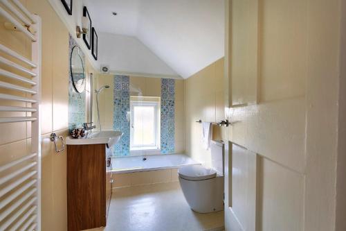 a bathroom with a sink and a toilet and a window at Finest Retreats - The Stables at Crimplesham in Stradsett