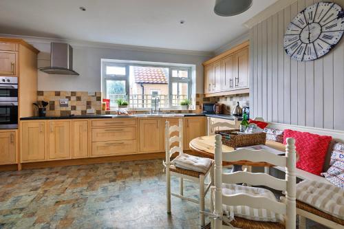 a kitchen with wooden cabinets and a table with chairs at Finest Retreats - The Stables at Crimplesham in Stradsett