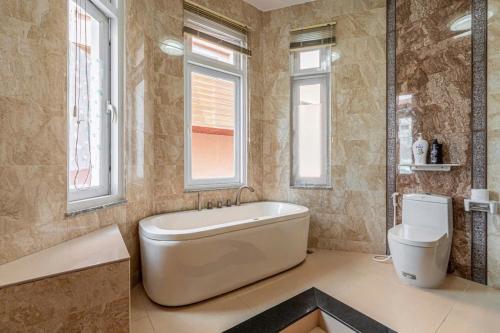 a bathroom with a tub and a toilet and windows at Villa La Rose Blanc Thảo Điền in Ho Chi Minh City