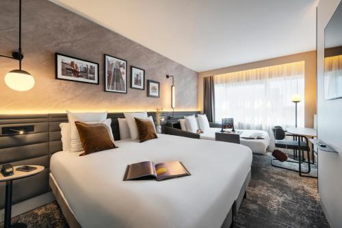 a hotel room with a large bed with a book on it at Novotel Paris La Défense Nanterre in Nanterre