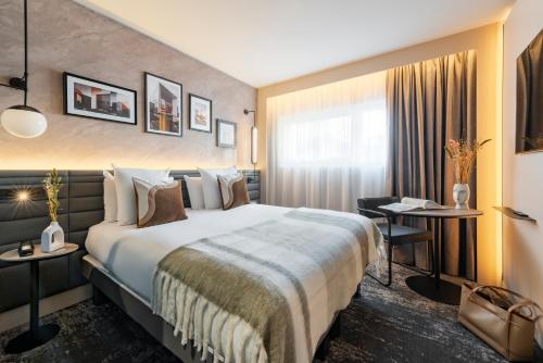 a hotel room with a large bed and a desk at Novotel Paris La Défense Nanterre in Nanterre