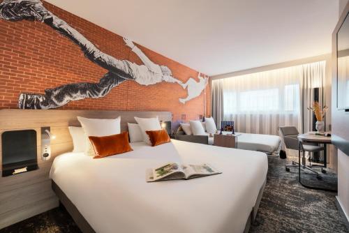 a hotel room with a large bed and a brick wall at Novotel Paris La Défense Nanterre in Nanterre