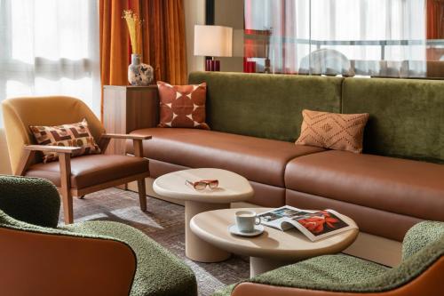 a living room with a brown couch and chairs at Novotel Paris La Défense Nanterre in Nanterre