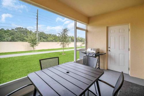 a patio with a table and chairs and a large window at SUPER BOHO CHIC Stylish Blend NEAR Disney in Kissimmee