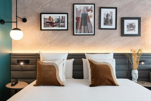a bedroom with a bed with four pictures on the wall at Novotel Paris La Défense Nanterre in Nanterre