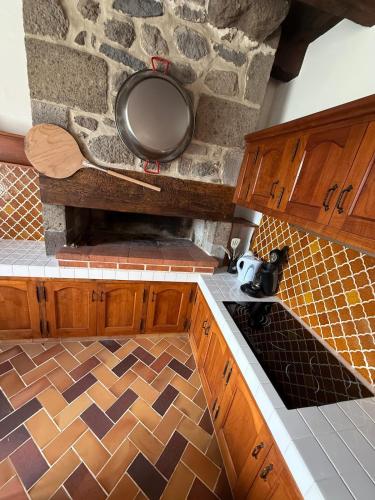 - une cuisine avec des placards en bois et un mur en pierre dans l'établissement La Maison du Colonel, à Sainte-Eulalie