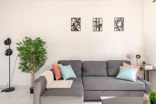 a living room with a gray couch and a plant at Loopafstand van Lokale Winkels en Zeedijk! - Prachtig Vakantiehuis! in Terneuzen