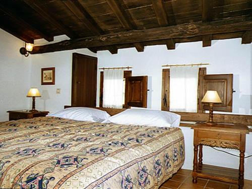 a bedroom with a bed with two lamps on a table at CR La Cueva CR-CC-00114 in Casas del Castañar
