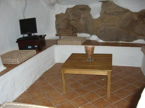 a living room with a table and a tv at Casa Rural La Cueva in Casas del Castañar