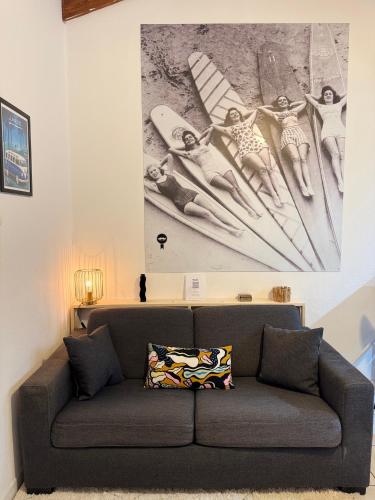 a couch in a living room with a painting on the wall at Blue Wave Patio, 5 mins à pied du centre Hossegor in Capbreton