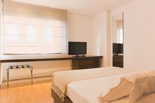 a bedroom with a bed and a window with a television at Hotel Hill House Usaquén in Bogotá