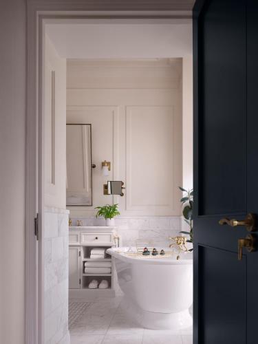 a white bathroom with a tub and a sink at Kimpton Fitzroy London by IHG in London