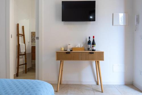 a table with wine bottles and a tv on a wall at Il Giardino del Tempio in Agrigento