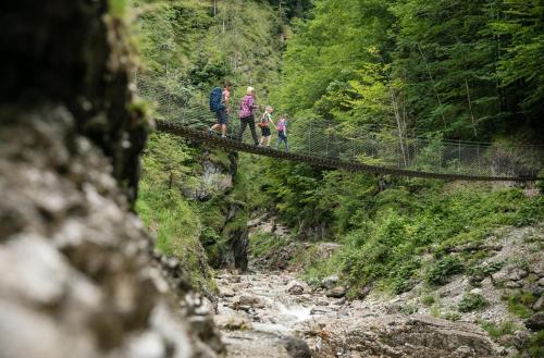 a group of people walking across a bridge over a river at pure mountain BASE in Erpfendorf