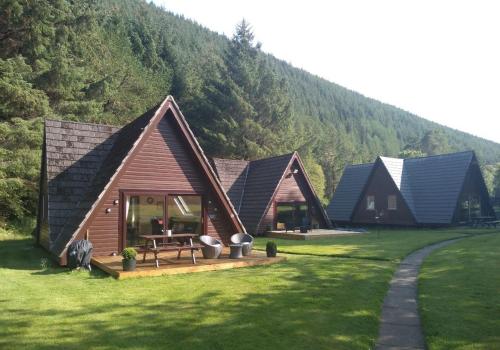 a row of cottages in a field with a mountain at True North Lodge - A cosy wee highland Getaway in Spean Bridge