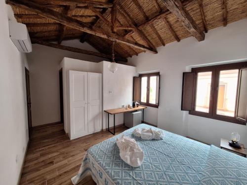 a bedroom with a bed and a table and windows at Dommu Amsicora Piano 2 in Baunei