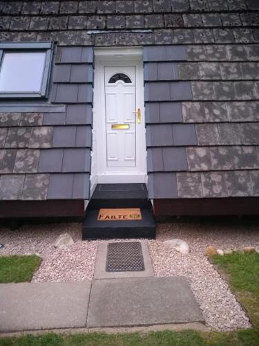 a white door on the side of a house at True North Lodge - A cosy wee highland Getaway in Spean Bridge