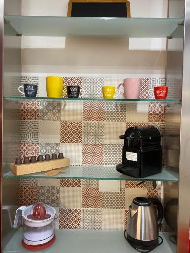 a shelf with cups and a coffee maker on it at Corte Prini Fiumicino in Fiumicino