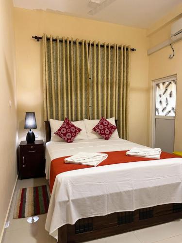 a bedroom with a large bed with red pillows at Lahiru Airport Villa in Andiambalama
