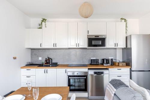 une cuisine avec des armoires blanches et une table en bois dans l'établissement GuestReady - Bright and Stylish Stay near Paris, à Saint-Ouen