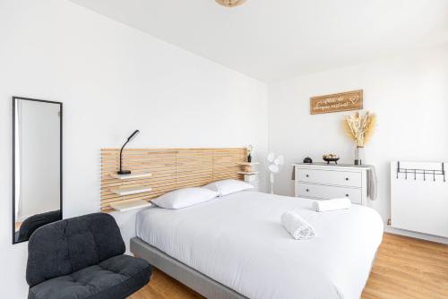 une chambre blanche avec un lit et une chaise dans l'établissement GuestReady - Bright and Stylish Stay near Paris, à Saint-Ouen