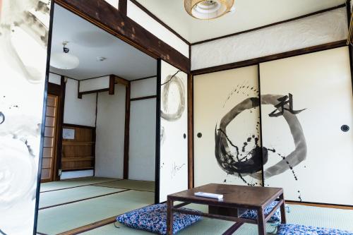 una habitación con una mesa y una pared con una pintura de un pájaro en Guest House Oku, en Nara