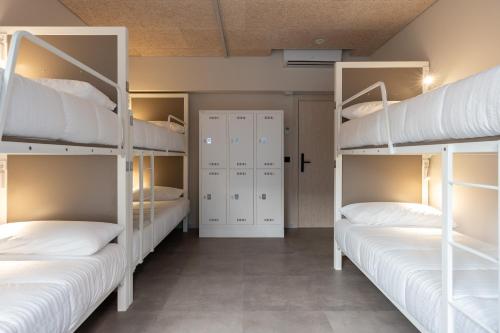 a room with three bunk beds with white pillows at Lamia BBK Women Hostel-Solo mujeres in Bilbao