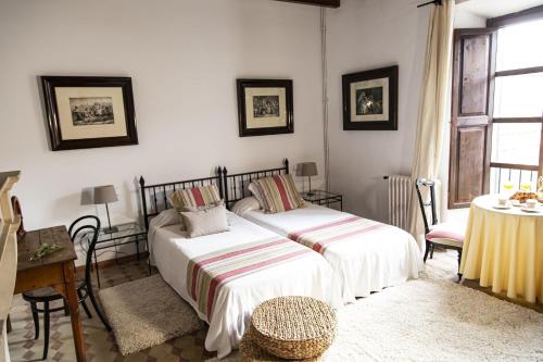 a bedroom with two beds and a table and a window at León de Sineu in Sineu
