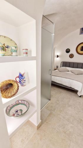 a white room with a bed and a shelf with plates at B&B La Casa Di Bianca in Manfredonia