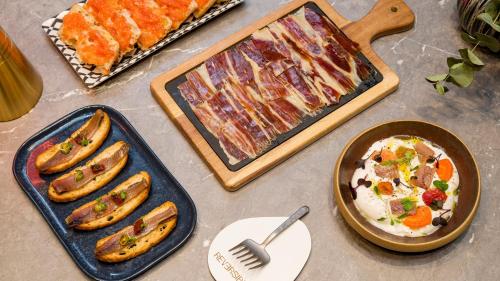 a table with different types of food and a pan of food at Hotel Indigo Barcelona Plaza Espana by IHG in Barcelona
