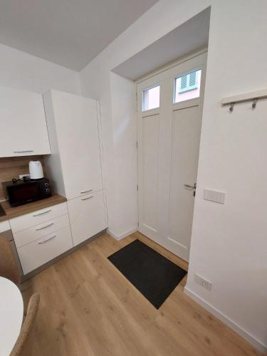 a kitchen with white cabinets and a door with a window at Casa Bùgia Nen in Alba