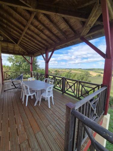 une terrasse en bois avec une table et des chaises dessus dans l'établissement Beautiful house with pool table in a green setting, à Lartigue