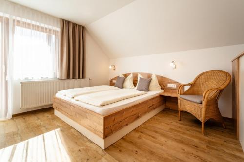 a bedroom with a wooden bed and a chair at Gästehaus Nemast in Weissensee