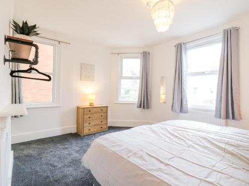 a white bedroom with a bed and two windows at The Wiltons in Bexhill