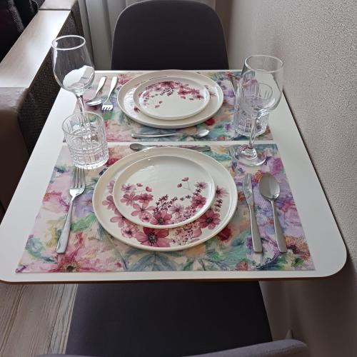 a table with a plate and wine glasses on it at Vienibas I Apartments in Daugavpils